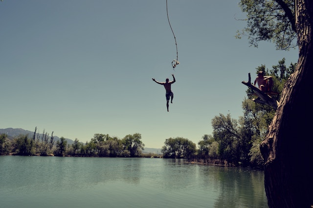 man jumping from swinging rope over lake, chapter writing adventure