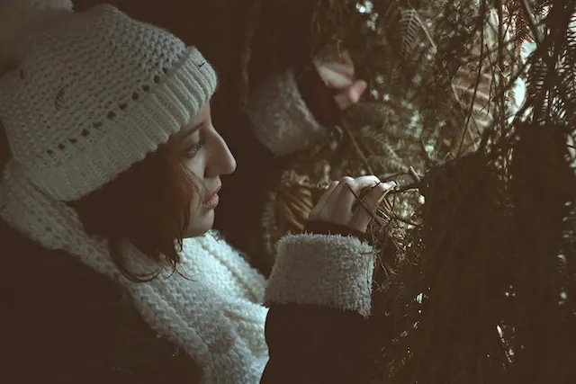 woman peering through shrubs