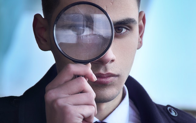 man peering through magnifying glass