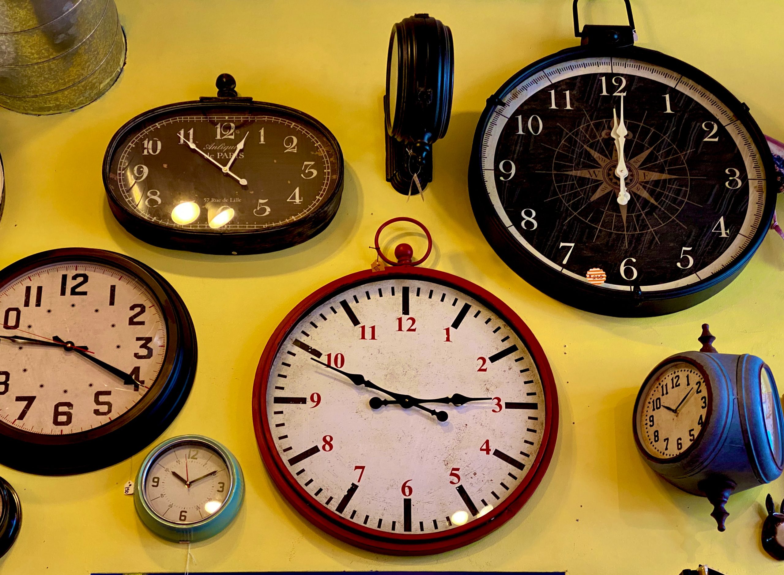 yellow wall with multiple clocks