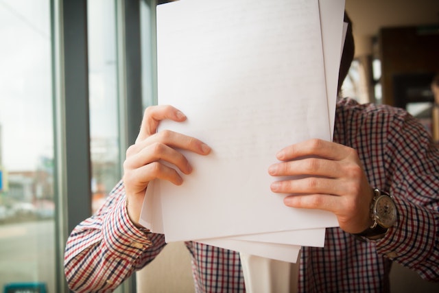 man holding papers in front of his face