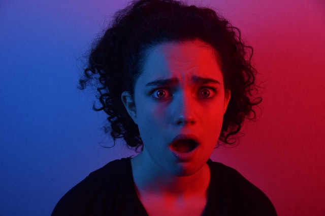 woman with surprised face in red and blue lighting