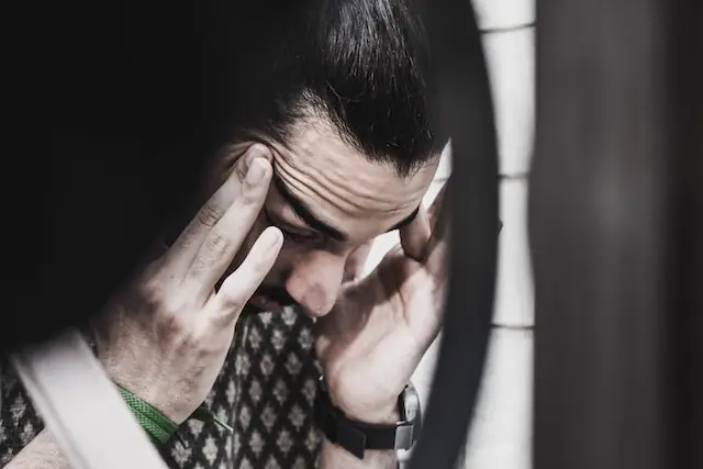man holding his temple with frowning forehead