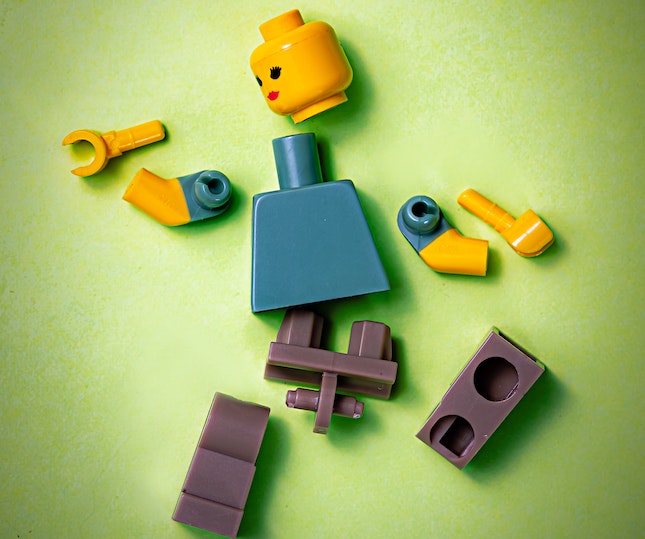 Lego figure in pieces ready to be assembled to illustrate character traits that comprise the protagonist sleuth.
