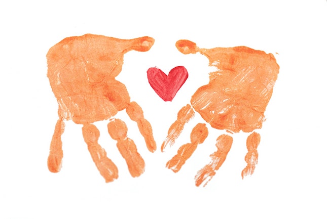 Two hand prints surrounding a red heart signifying self-care.