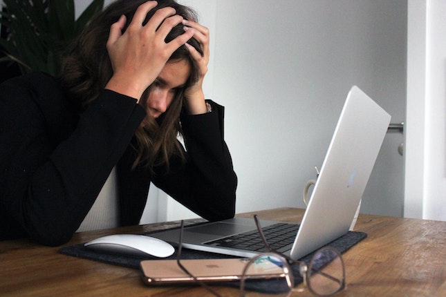 woman staring at computer screen in frustration stalling her writing