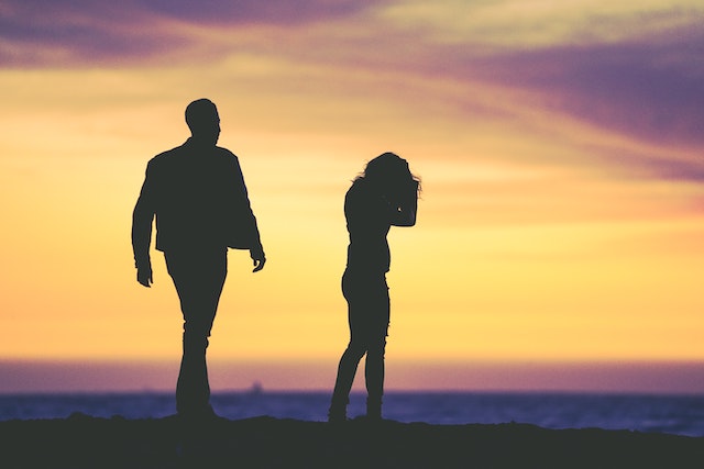 man approaching woman on a beach at sunset