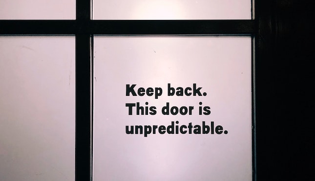 Door window sign: Keep back. This door is unpredictable.