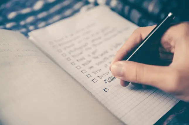 hand with pen making a list in a notebook