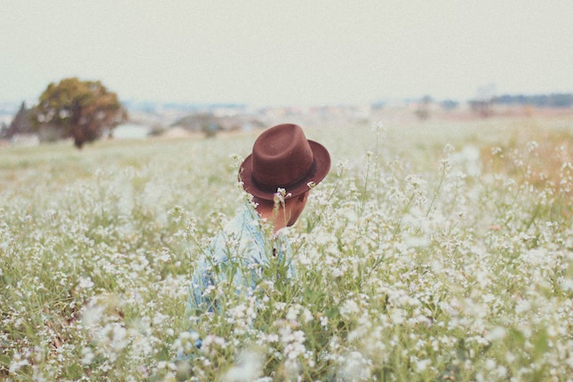 brown hatted man in a field of white flowers illustrating experiential setting
