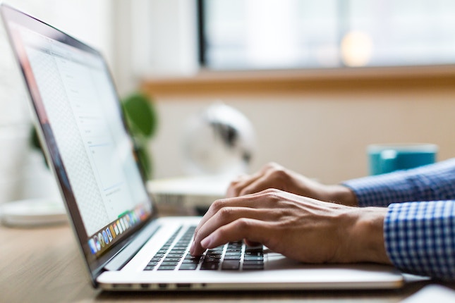 man's hands typing on a laptop keybord illustrating top 5 skills every mystery writer needs