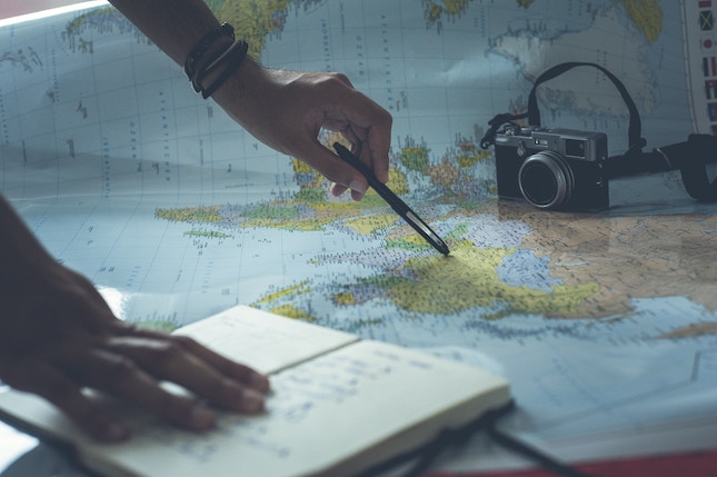 hand pointing to map and holding open notebook to illustrate mystery writing